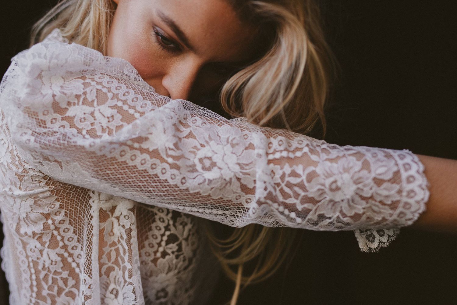 Close-up detail of delicate white lace sleeve from a wedding dress.