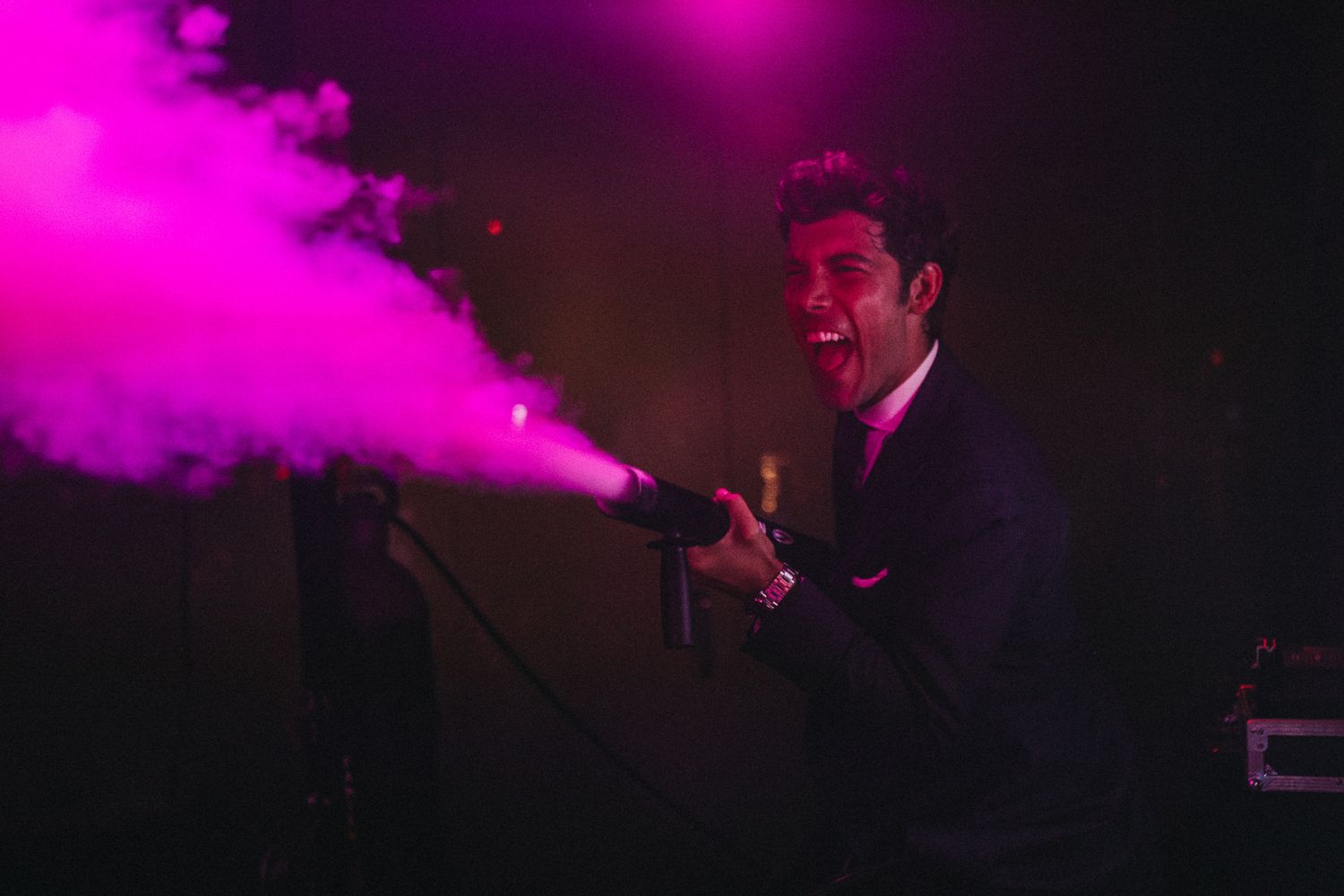 Pink smoke effect creates dramatic atmosphere during wedding reception performance.