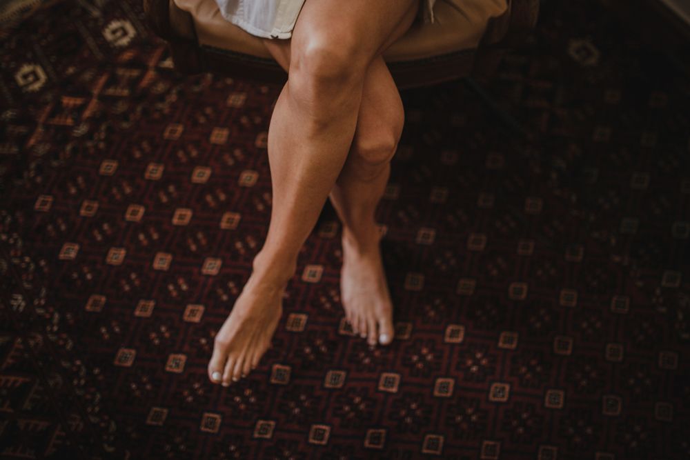 Bare feet resting on a patterned carpet in warm lighting.