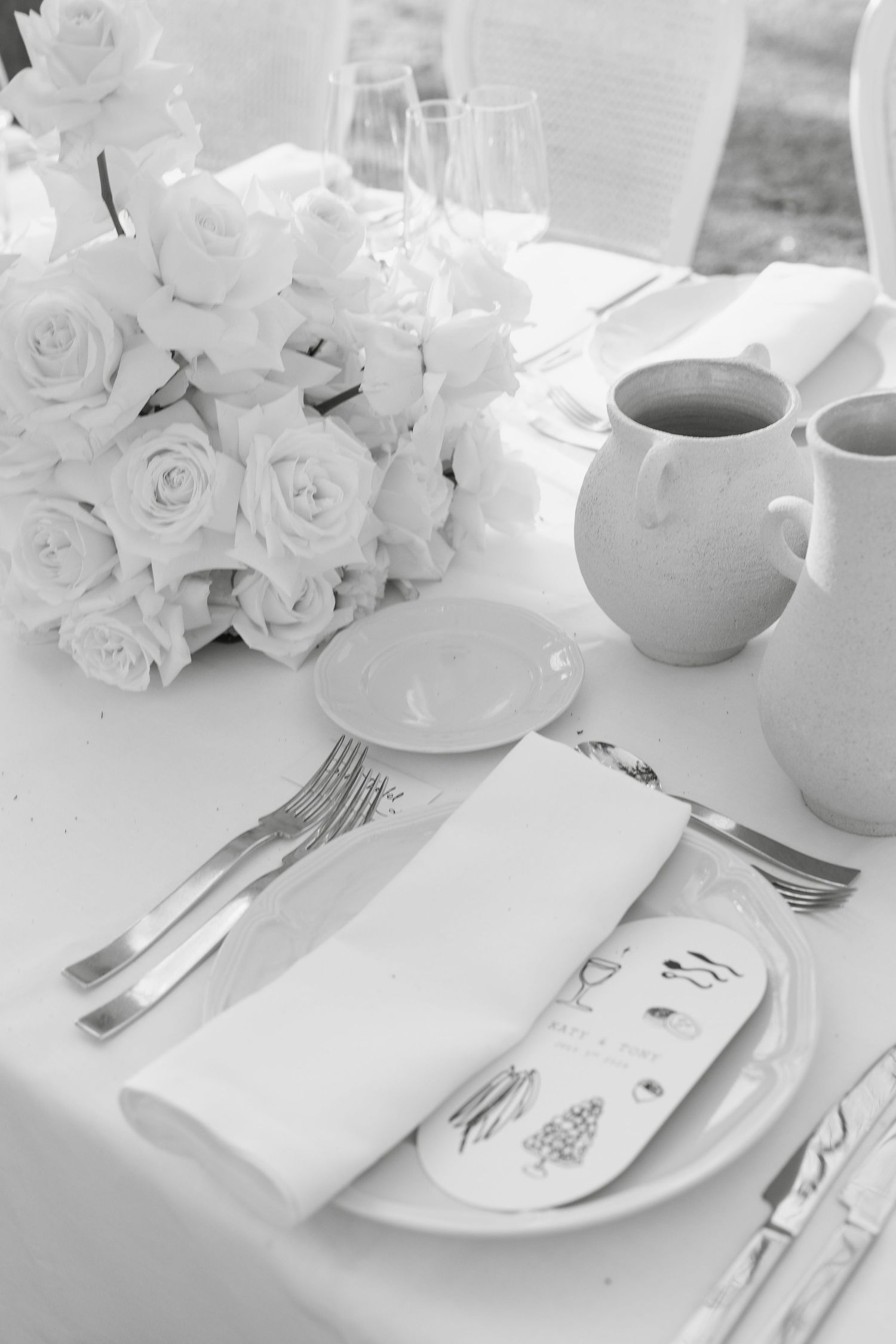 Classic white wedding table setting with roses, coffee cups and elegant place settings.