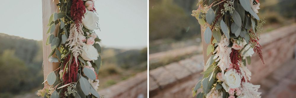 Dried floral arrangements with eucalyptus and burgundy blooms along train tracks.