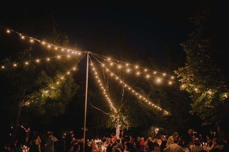 Outdoor wedding reception under string lights with guests celebrating at night.