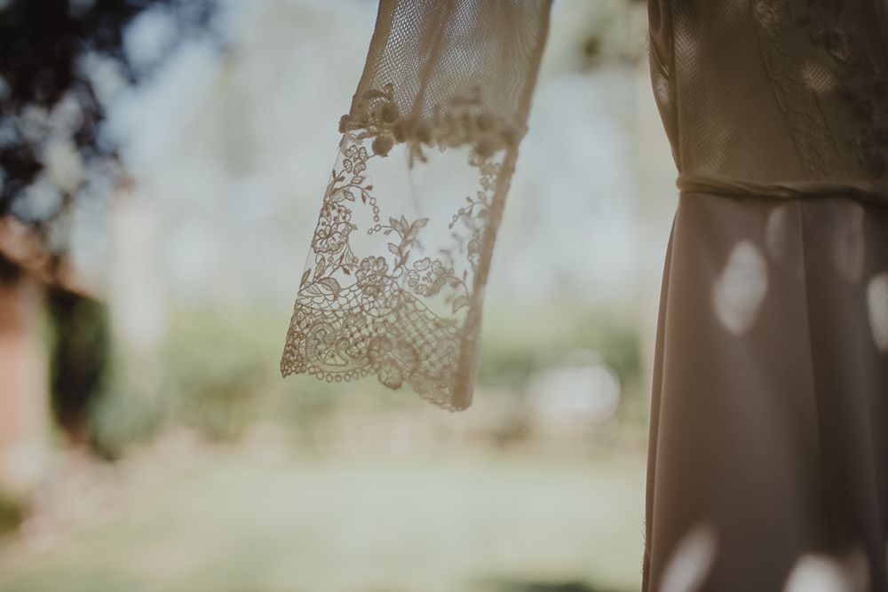 Delicate lace detail of wedding dress fabric captured in soft natural light.