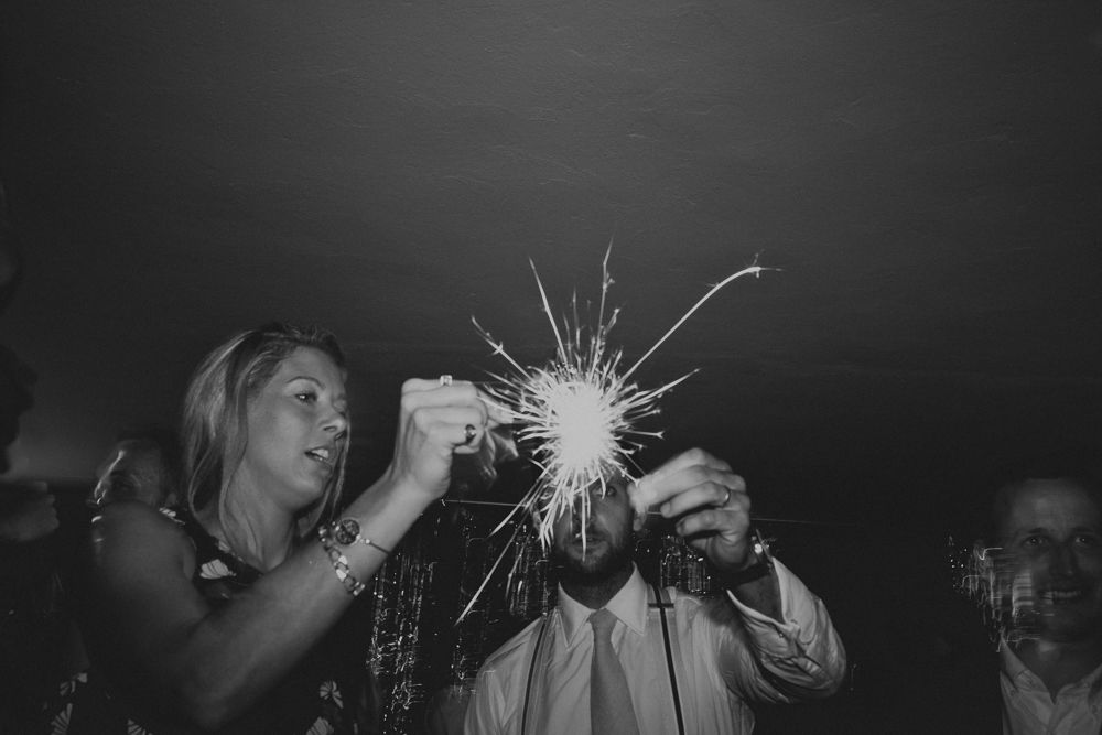 A sparkler creates bright streaks of light against dark background at a celebration.