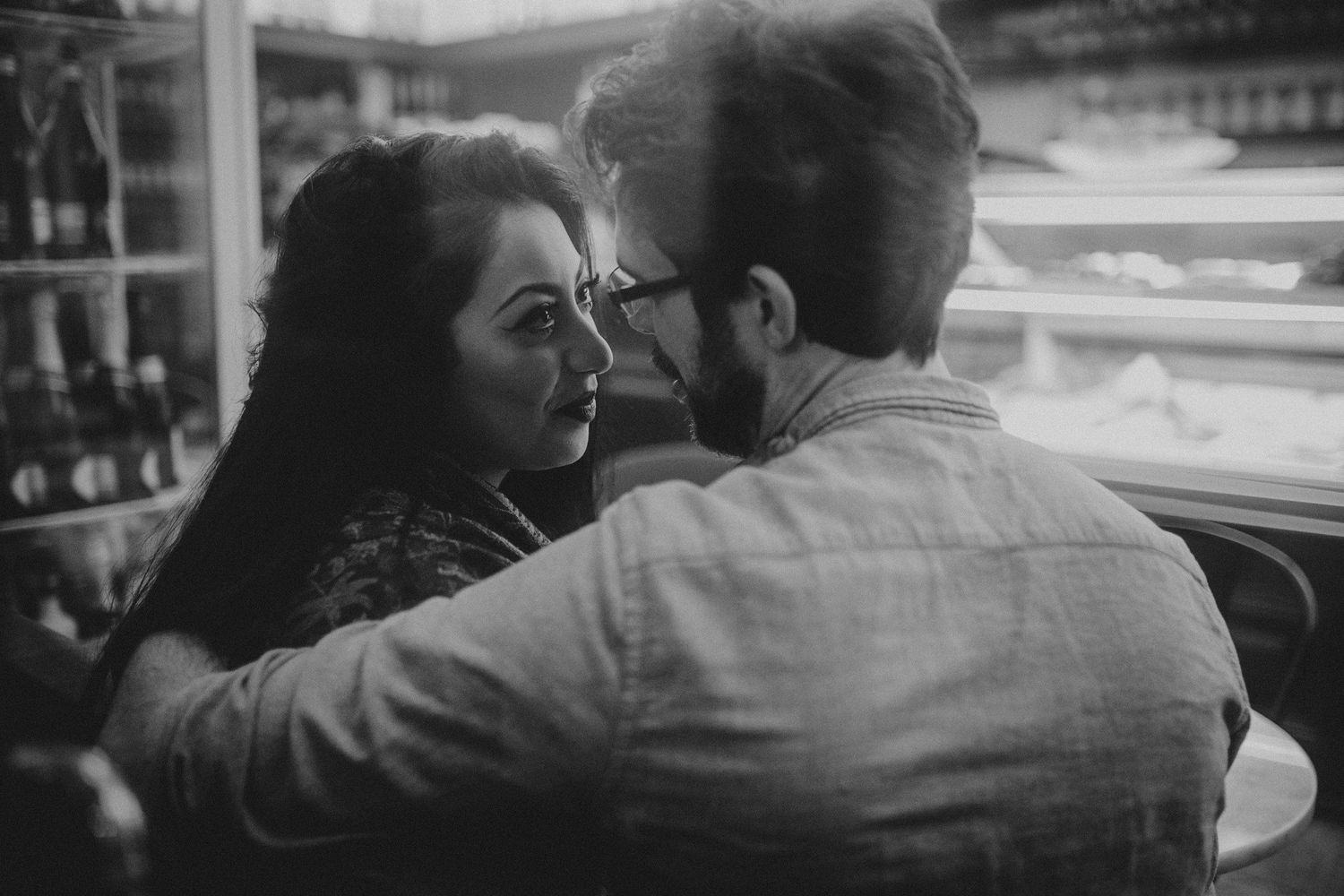 A black and white photo of a couple sharing a tender moment indoors.