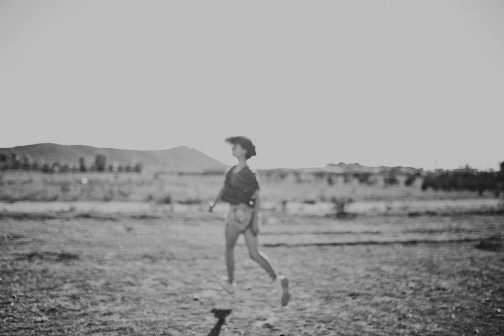 A person runs freely through an open desert field captured in black and white photography.