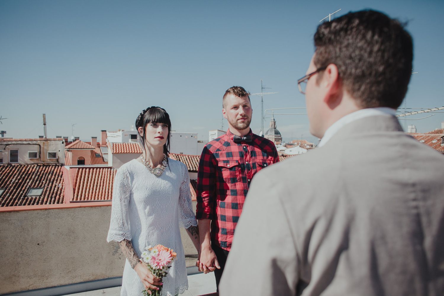 Three people having conversation on sunny rooftop terrace.