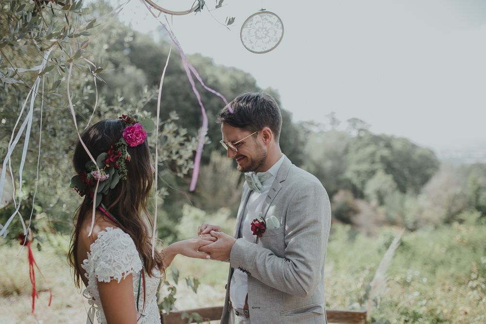 Intimate exchange of rings during an outdoor garden wedding ceremony with guests watching.