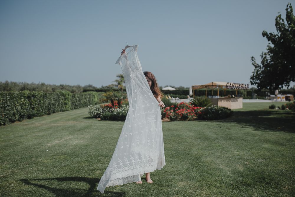 White wedding dress flowing in the breeze against garden landscape.