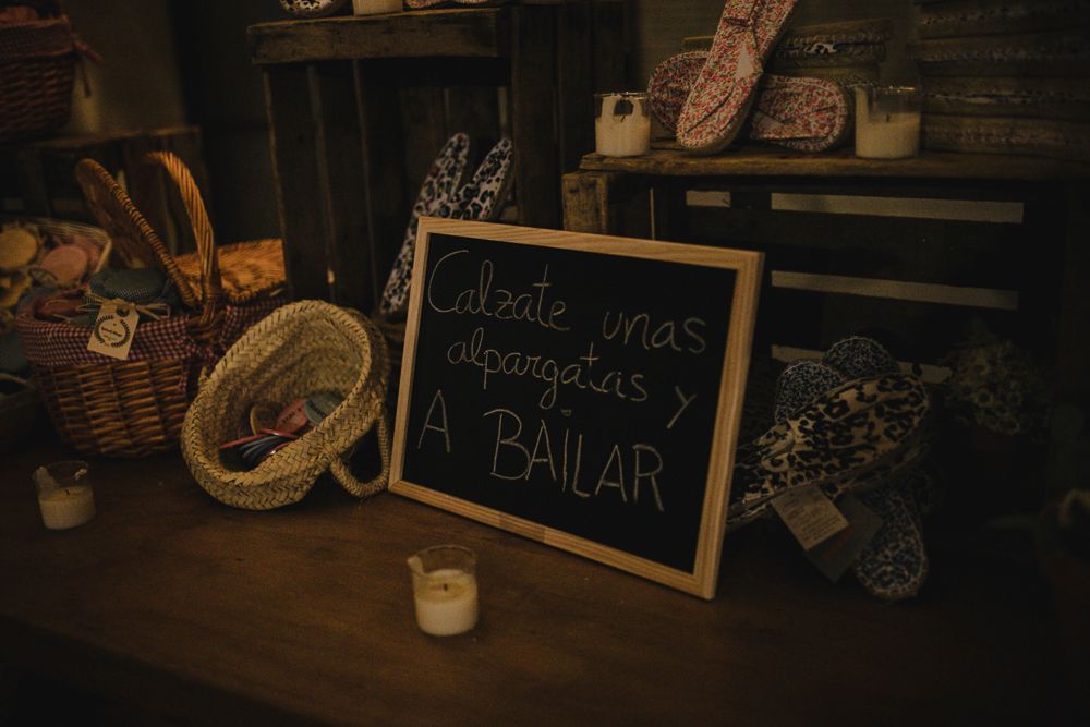 Rustic chalkboard sign reading 'A BAILAR' with decorative elements and candles.