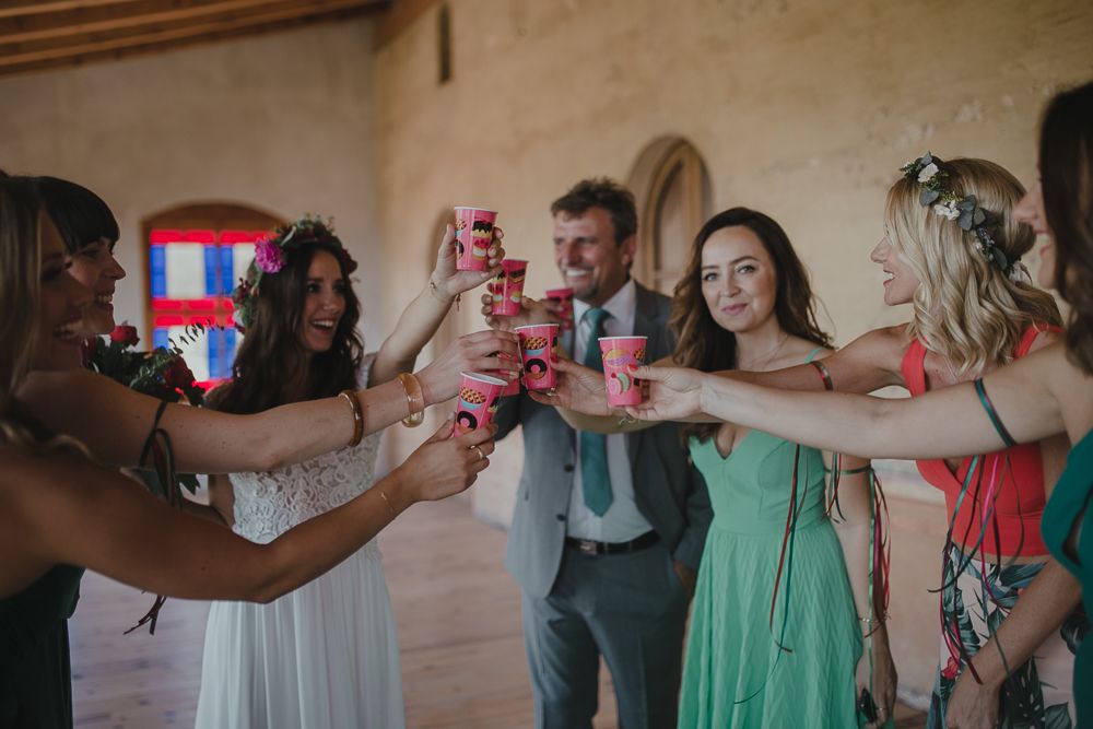Wedding party toasting with red cups during celebration.