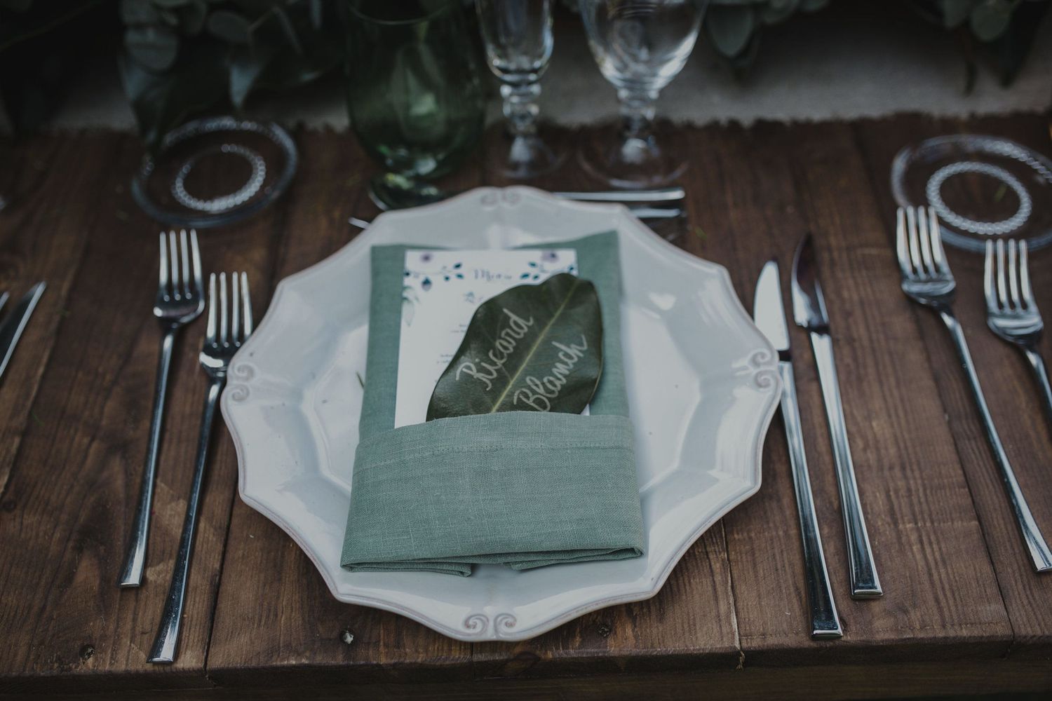 An elegant place setting with menu card on a rustic wooden table.