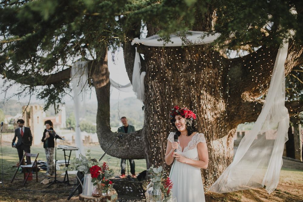 A beautiful outdoor wedding setup with fairy lights and white drapes hanging from a majestic tree.