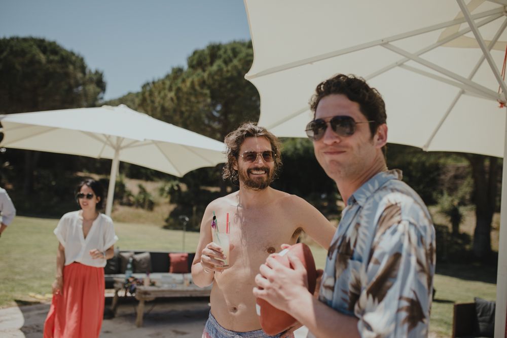 Casual outdoor summer party with parasols and guests enjoying drinks.
