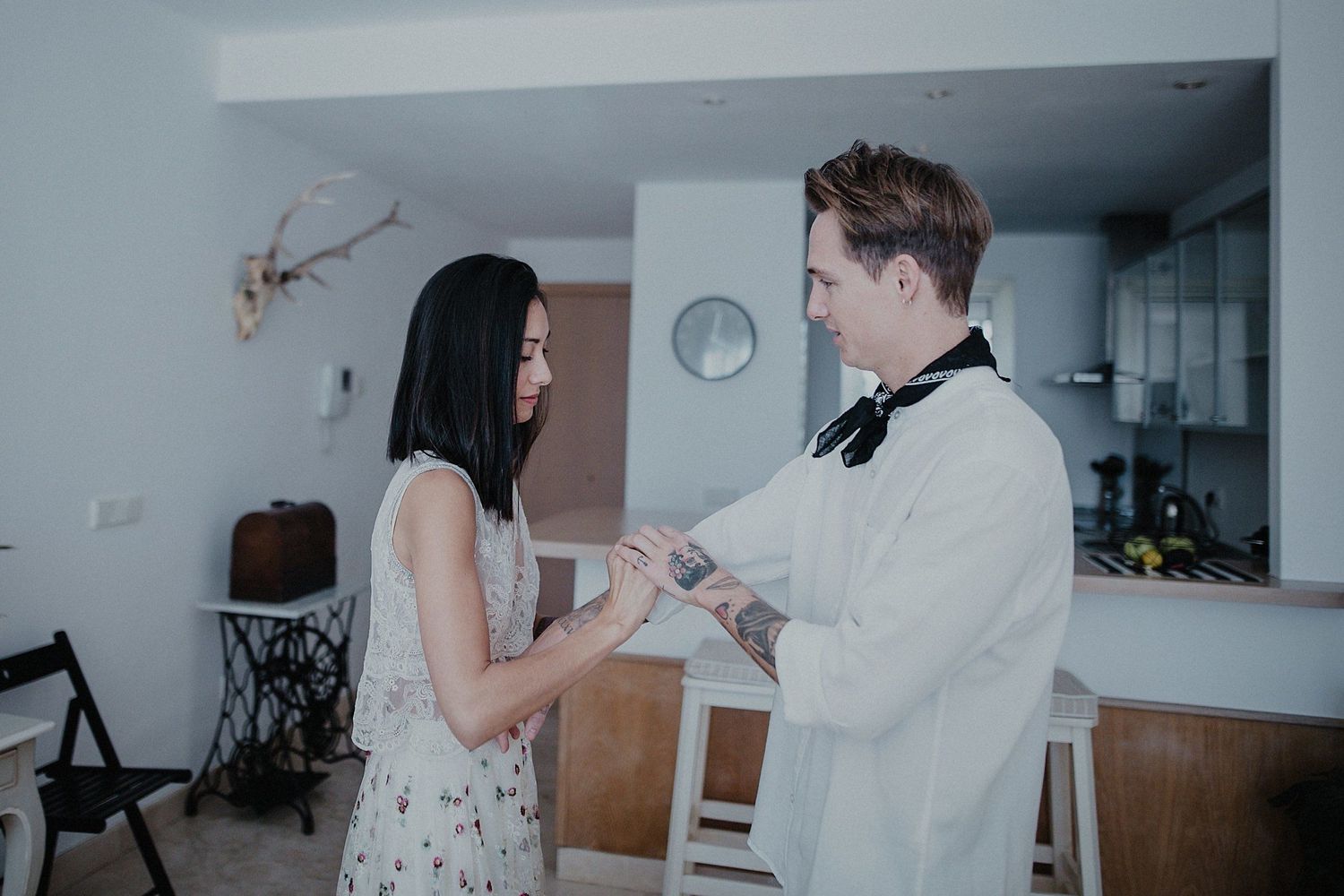 A couple in formal attire exchanging papers or vows in a minimalist room.