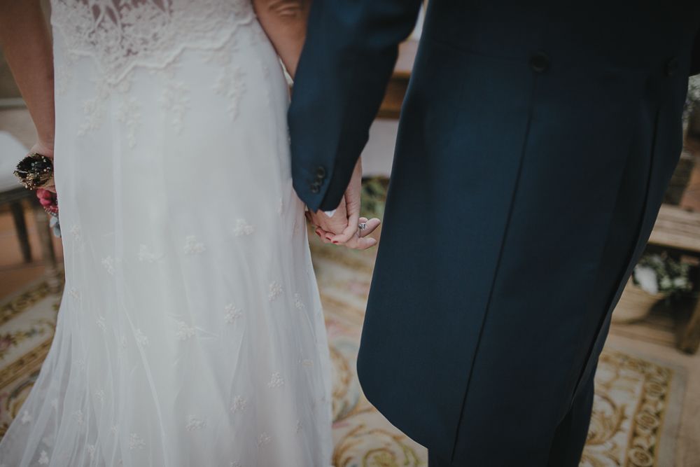 Close-up detail of wedding dress and suit at formal ceremony.