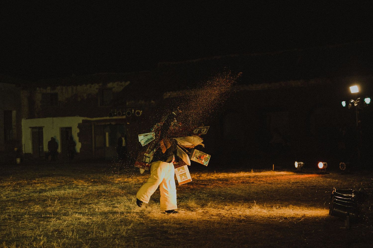 Two dancers perform an intimate dance under outdoor lighting against a dark building backdrop.