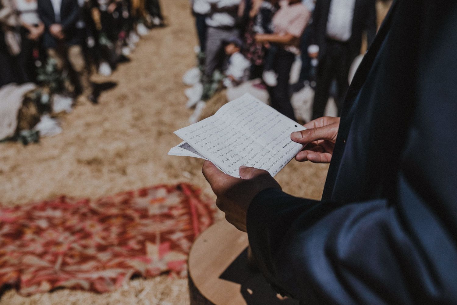 A close-up shot of hands holding written vows during an outdoor ceremony.