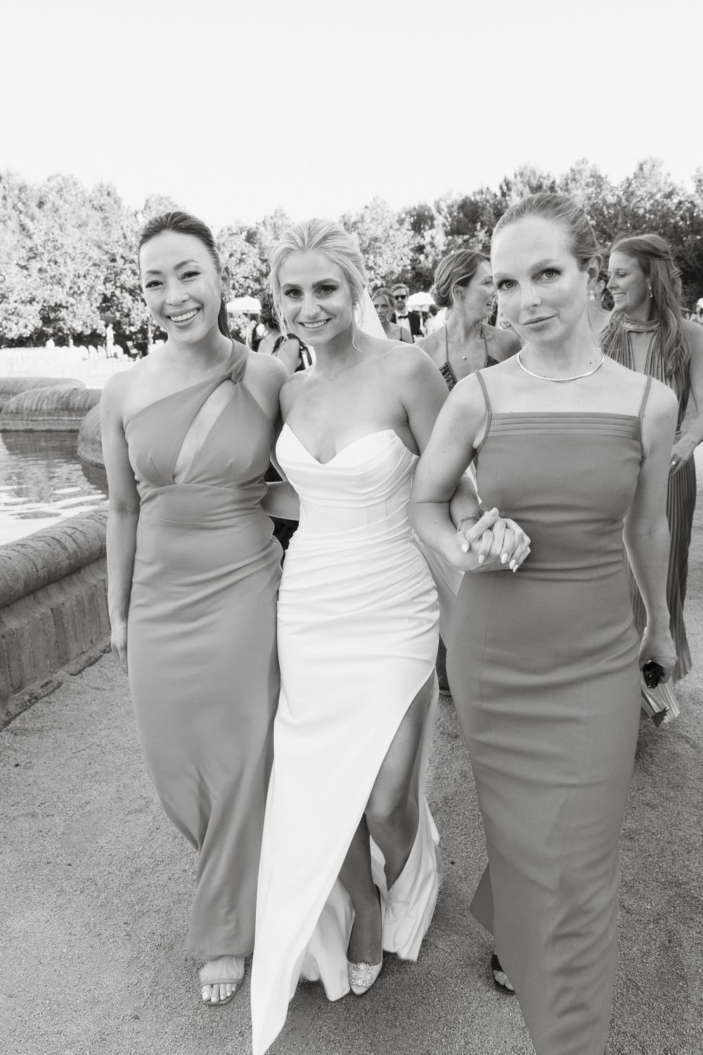 Wedding party members in gray dresses and white gown pose together outdoors.