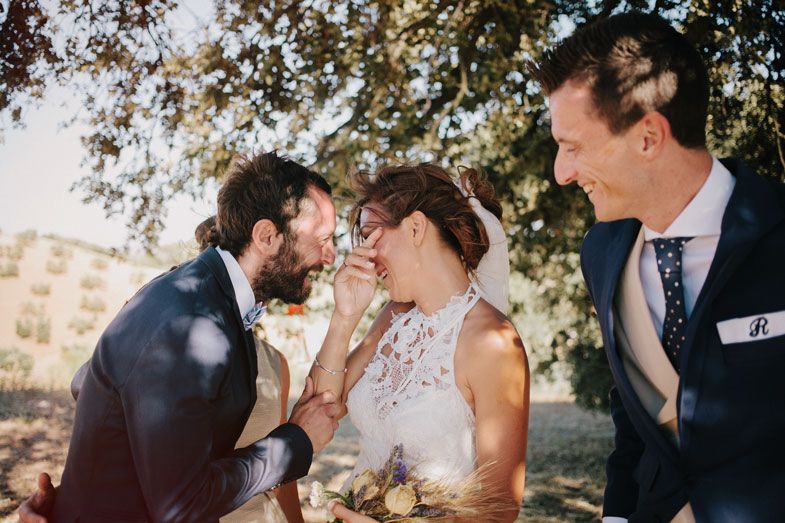 Intimate moment shared between wedding couple with guest smiling in background.