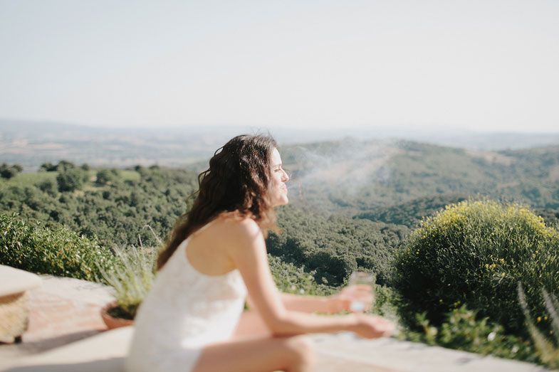 Bride overlooking scenic Tuscan hills from a terrace in her wedding dress.