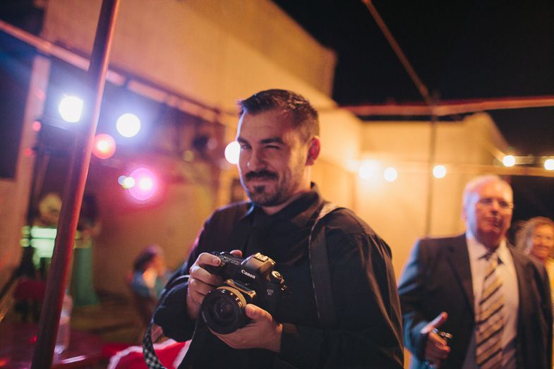 A photographer reviews images on their camera at a nighttime event with colorful lighting.