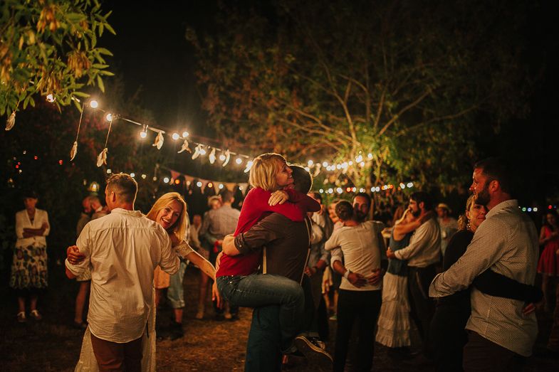 Guests dancing and celebrating at a nighttime outdoor party under twinkling string lights.