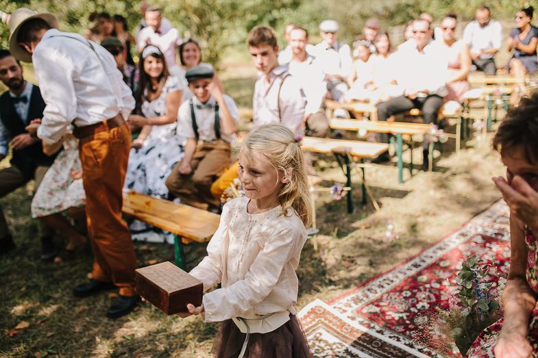 Guests seated on wooden benches during an outdoor wedding celebration.