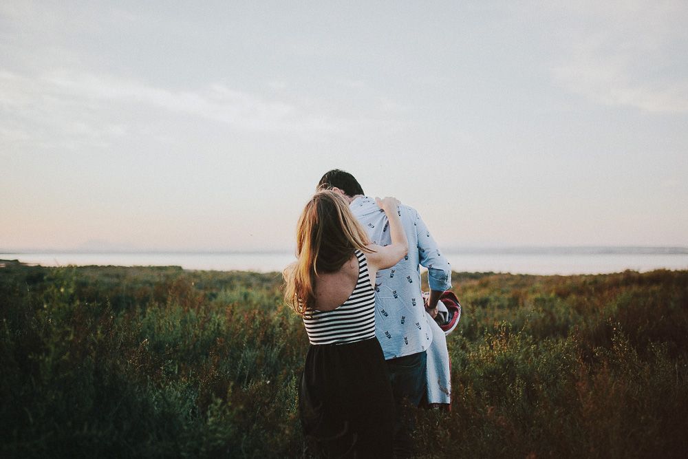 Couple holding each other close in a field at dusk.