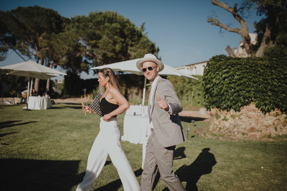 Stylish couple dancing together at outdoor wedding reception with trees in background.