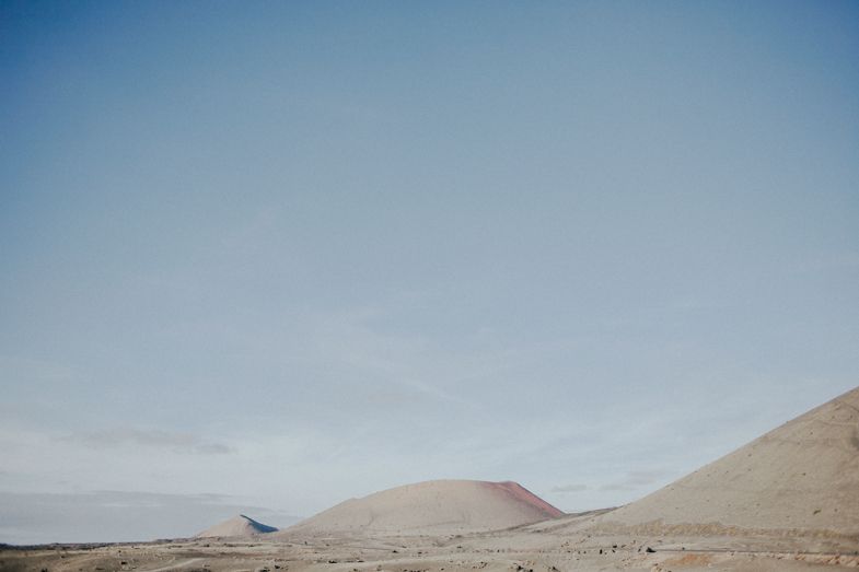 Desert landscape with rolling sand dunes and hills under a bright blue sky.