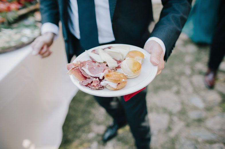 A plate of assorted meats and cheeses being held at an outdoor event.