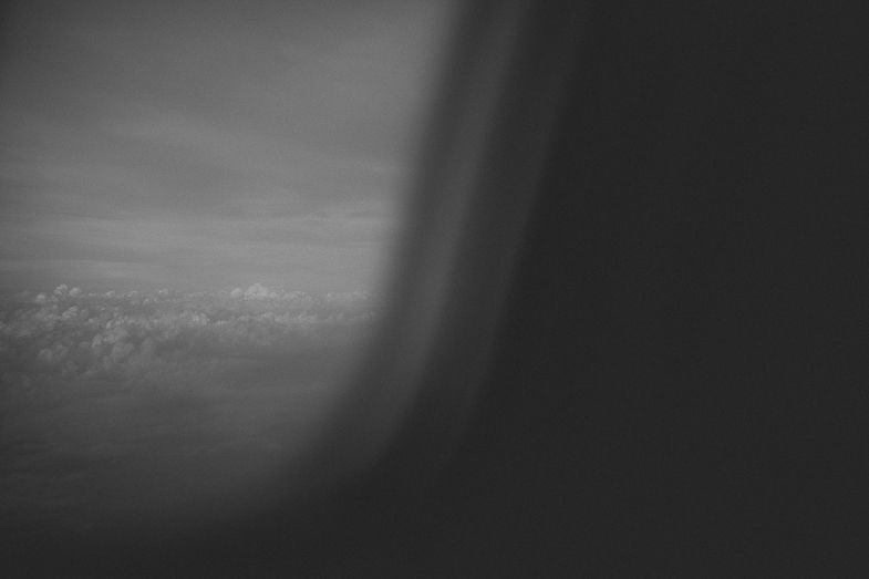 Aerial view through an airplane window during flight at sunset.