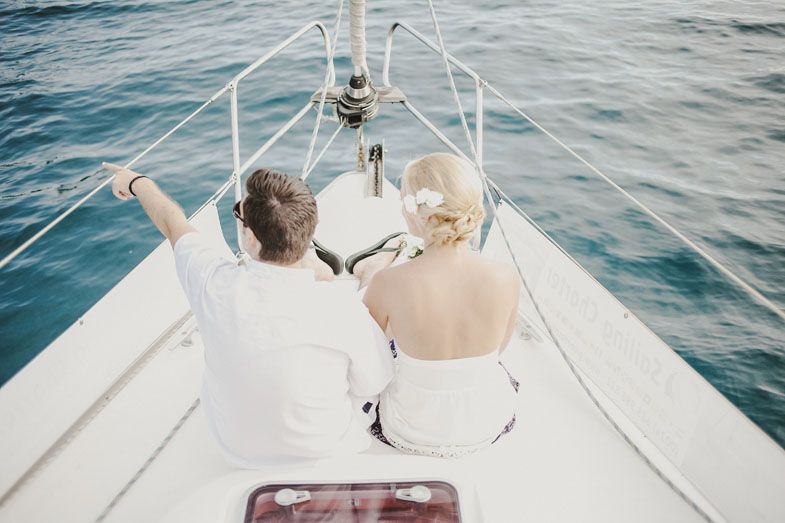 A couple relaxing on the bow of a boat sailing through blue waters.
