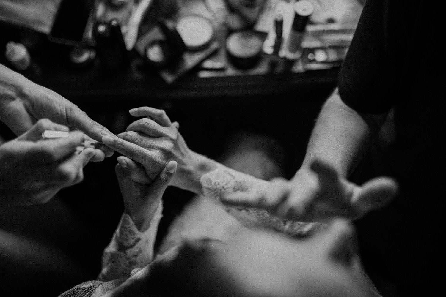 Close-up of hands applying makeup in black and white photography.