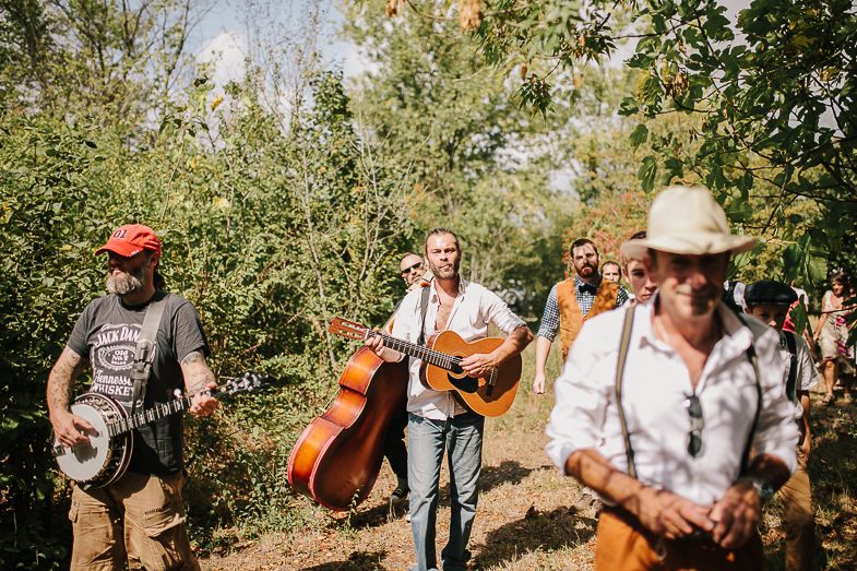 Musicians with guitars and upright bass perform at outdoor wedding celebration.