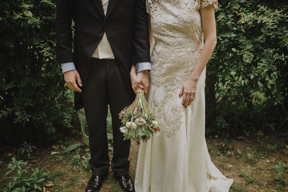 Artistic wedding portrait showing couple's attire against green garden backdrop.