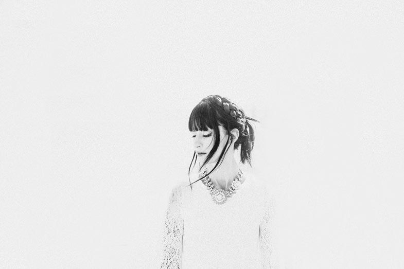 High-key portrait of a woman in white against a bright background.