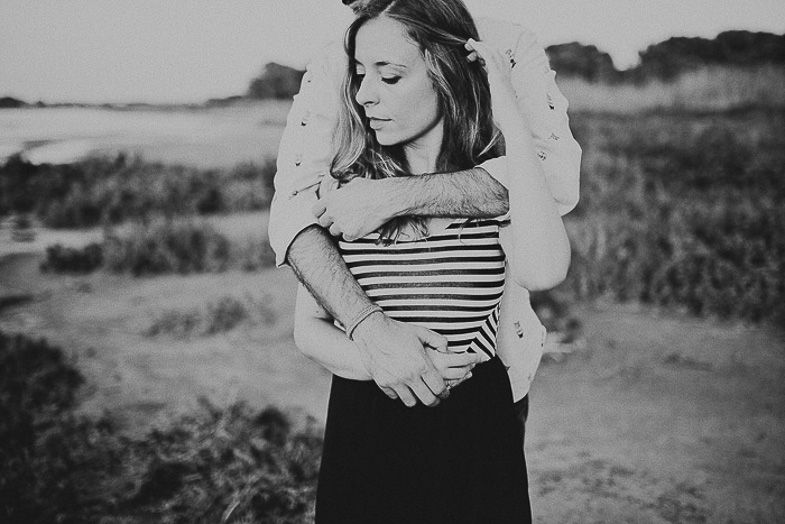 A tender embrace captured in black and white against a natural outdoor landscape.