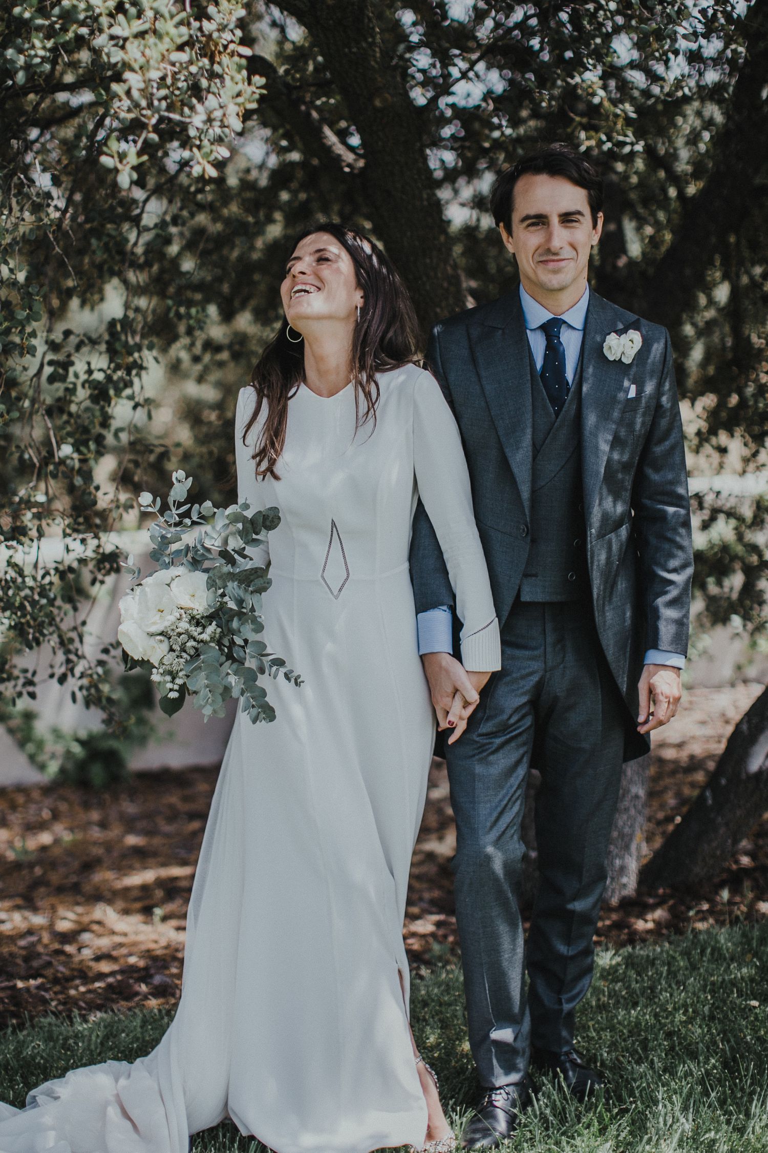 A joyful wedding moment captured under blooming spring trees.