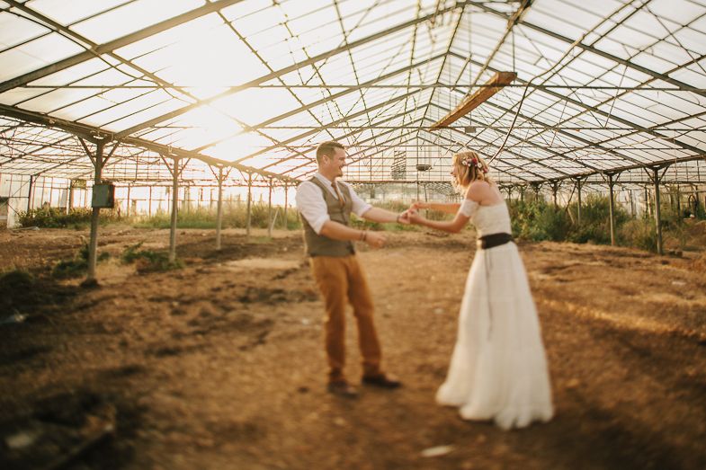 Couple sharing a romantic moment in a sunlit greenhouse during their wedding.