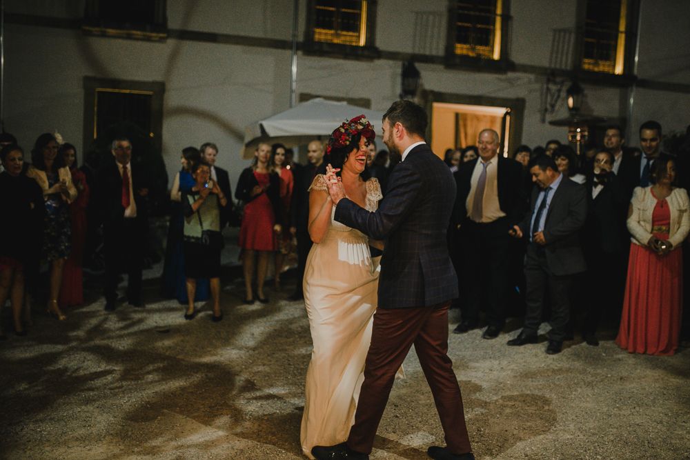 Romantic first dance at evening wedding reception with guests watching.