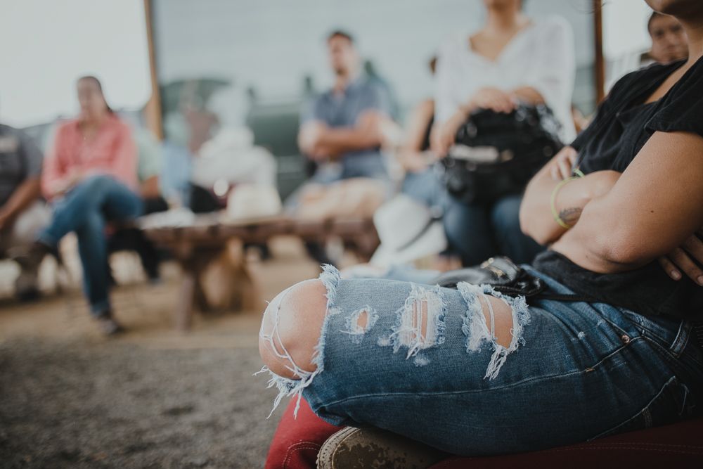 People sitting on outdoor benches wearing casual clothing in soft focus.