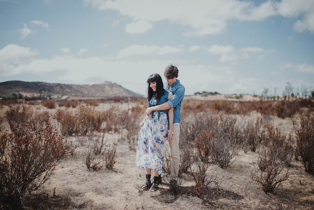 A romantic moment captured in a desert setting with mountains and blue skies.