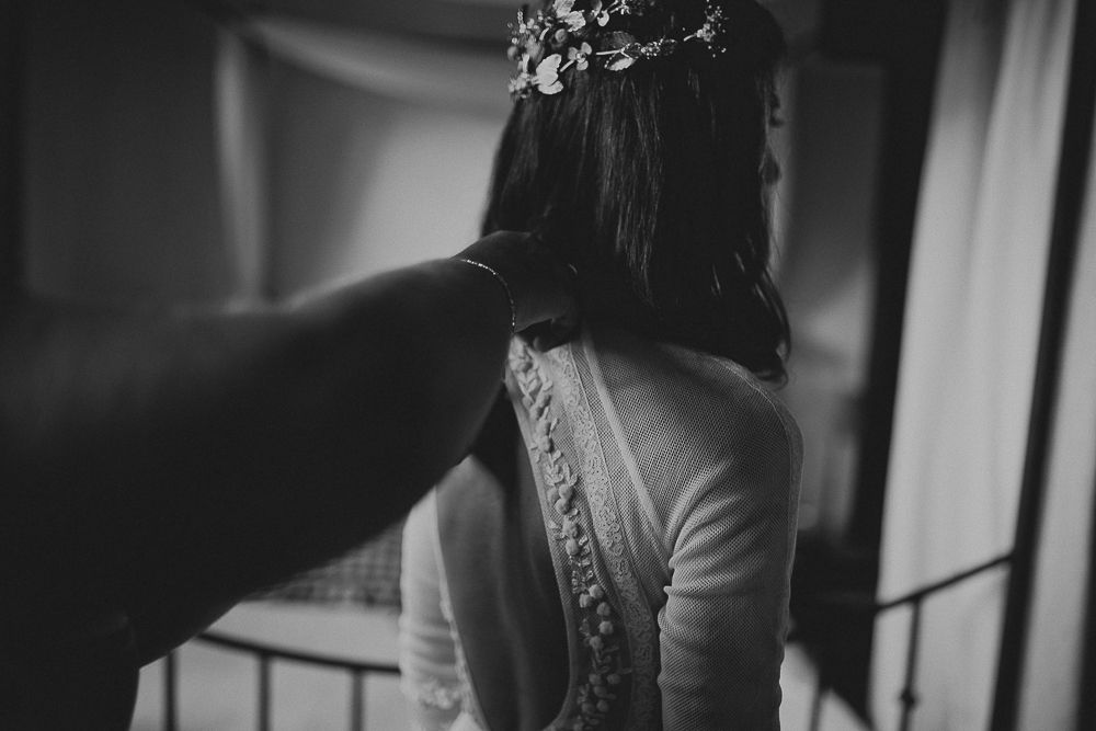Black and white detail shot of hands adjusting the back of a wedding dress.