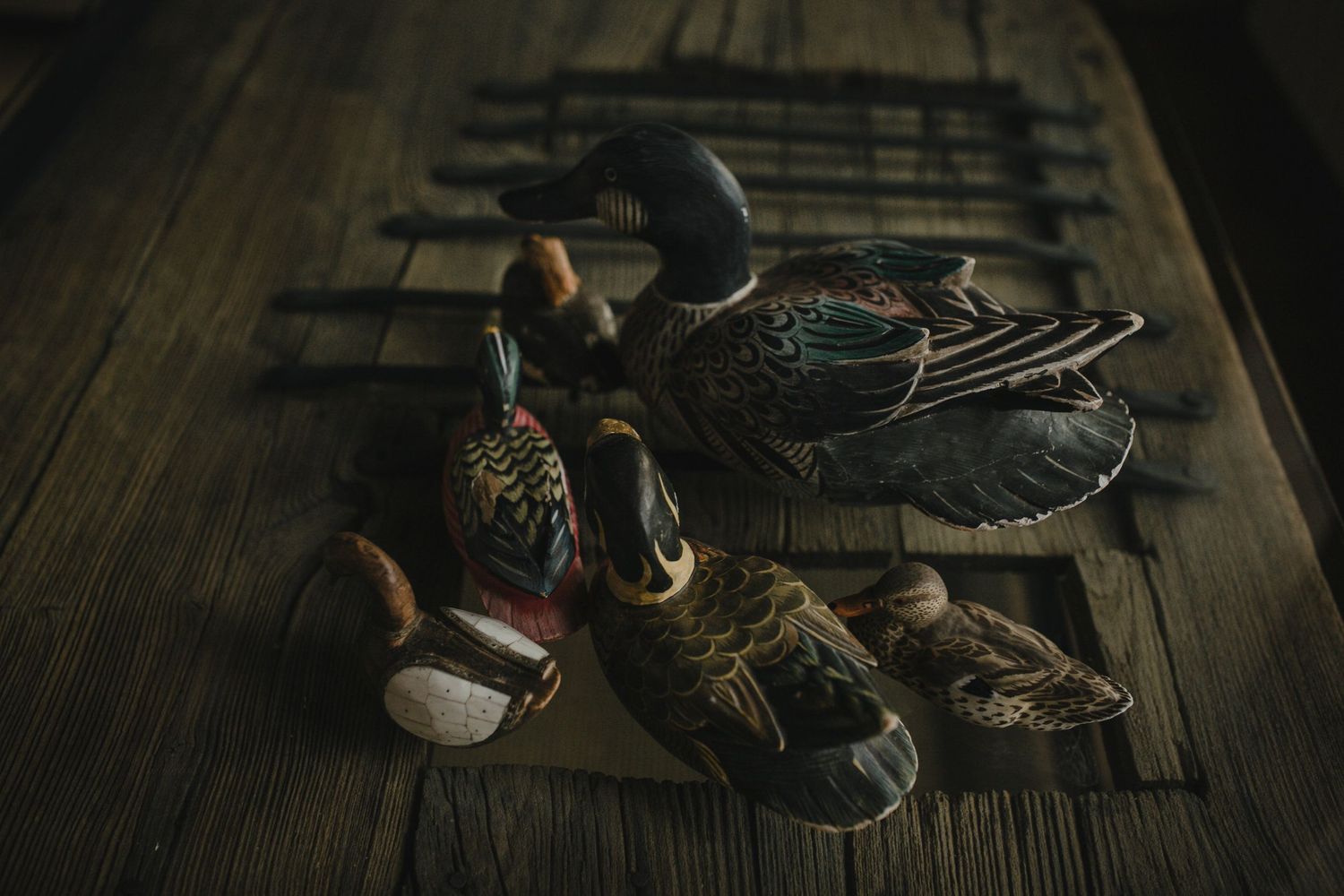 Several old worn-out shoes and boots arranged on a rustic wooden floor in moody lighting.