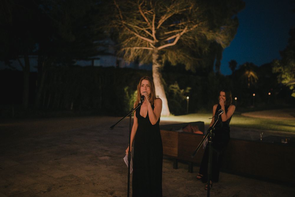 Performers in black dresses on stage at outdoor nighttime event.