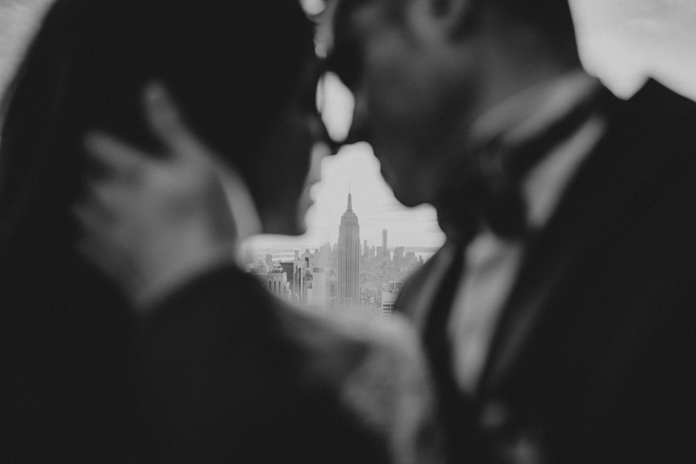 Artistic black and white wedding photo framing the Empire State Building between silhouetted figures.