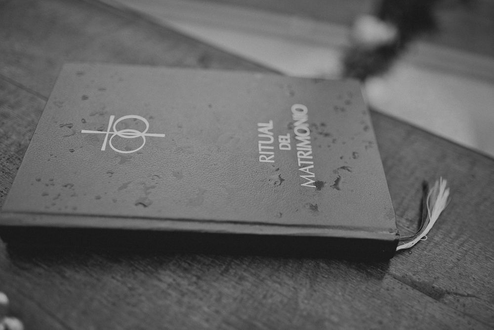 A worn book with minimalist design lies on a wooden surface in black and white.
