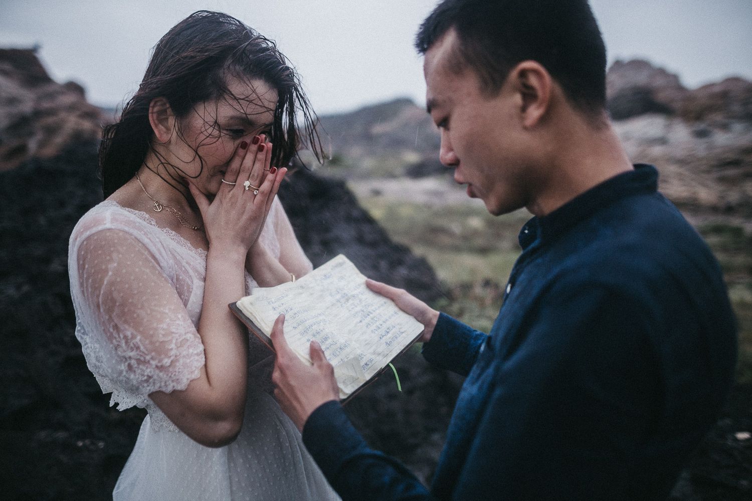 An emotional moment as a couple reads from a book together in a dramatic outdoor setting.